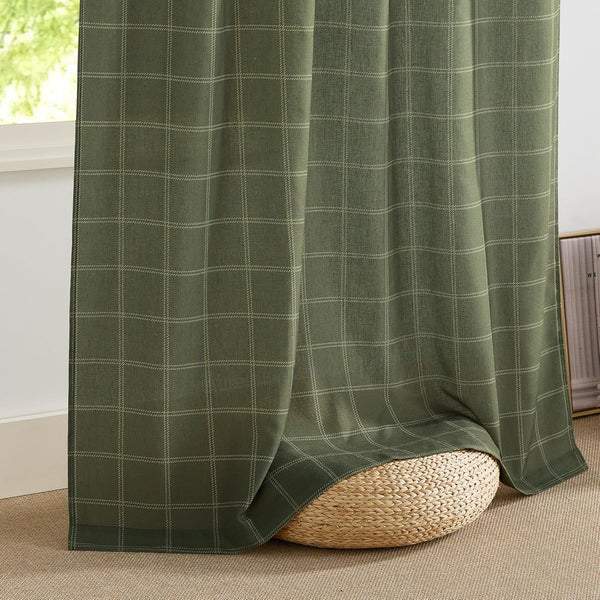 Textured olive green window curtain with subtle plaid pattern, draped beside a bright window.