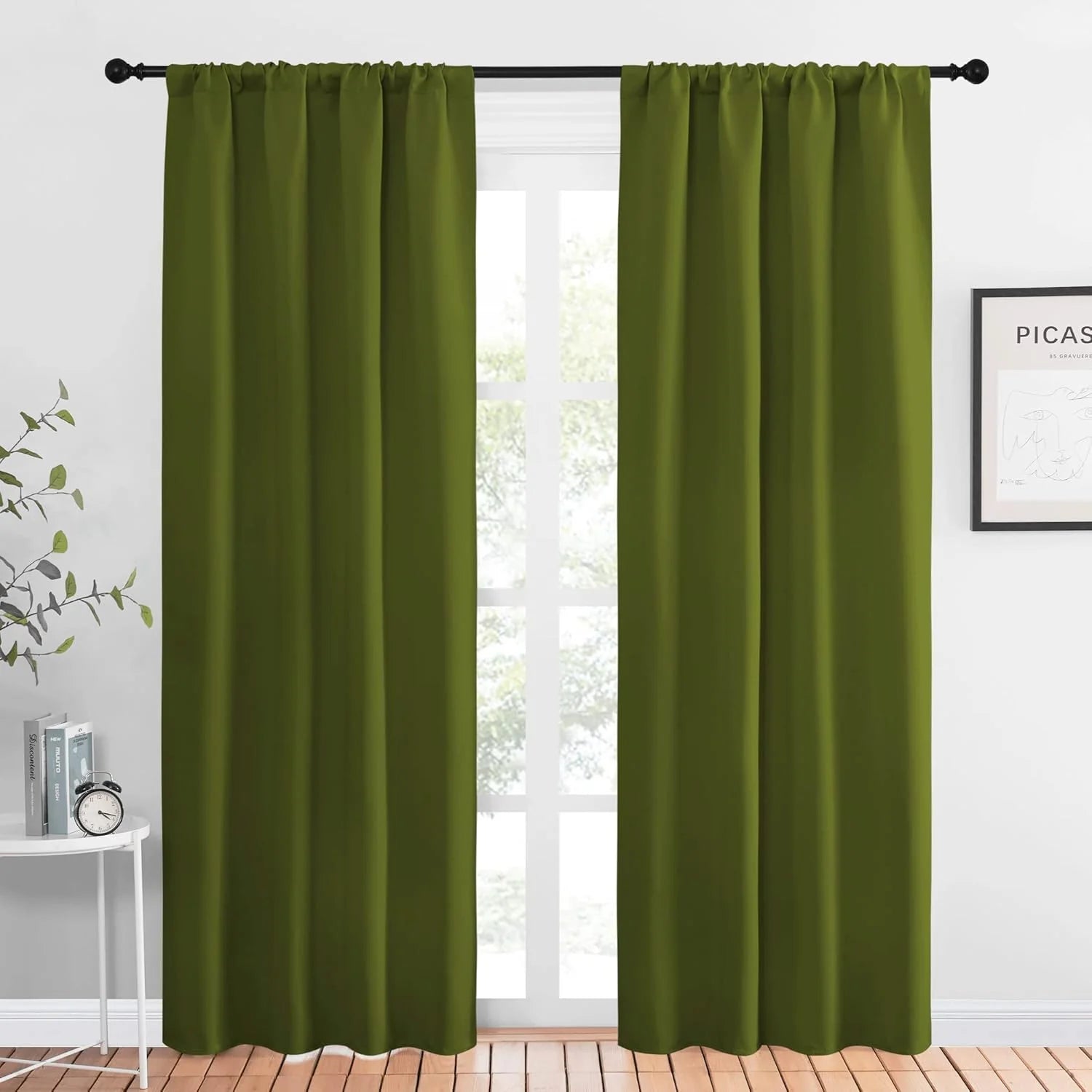 Olive green rod pocket curtains hanging on a black curtain rod in a bright modern room