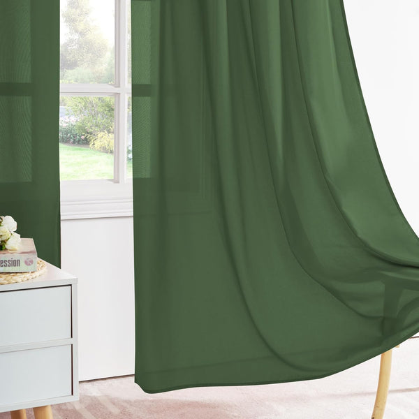 Flowing olive green sheer curtains framing a bright window overlooking a lush outdoor garden.