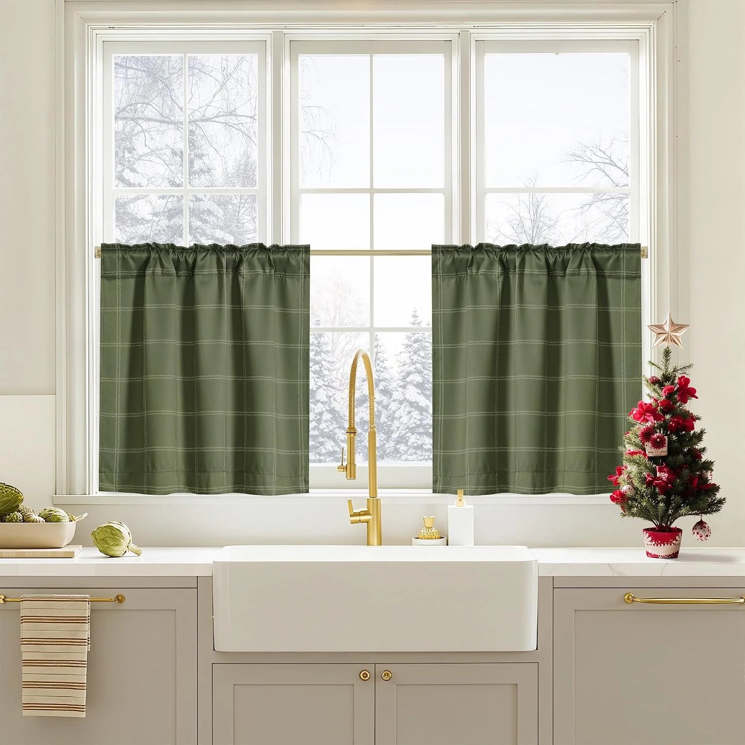 Olive green plaid cafe curtains over a bright kitchen sink window with brass faucet