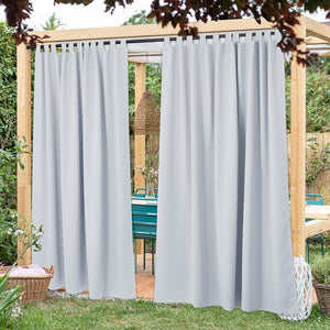 Light gray tab top outdoor curtains hanging on a wooden pergola in a garden setting.