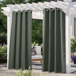 Two dark green outdoor privacy curtains with silver grommet tops hanging from a white pergola on a patio.