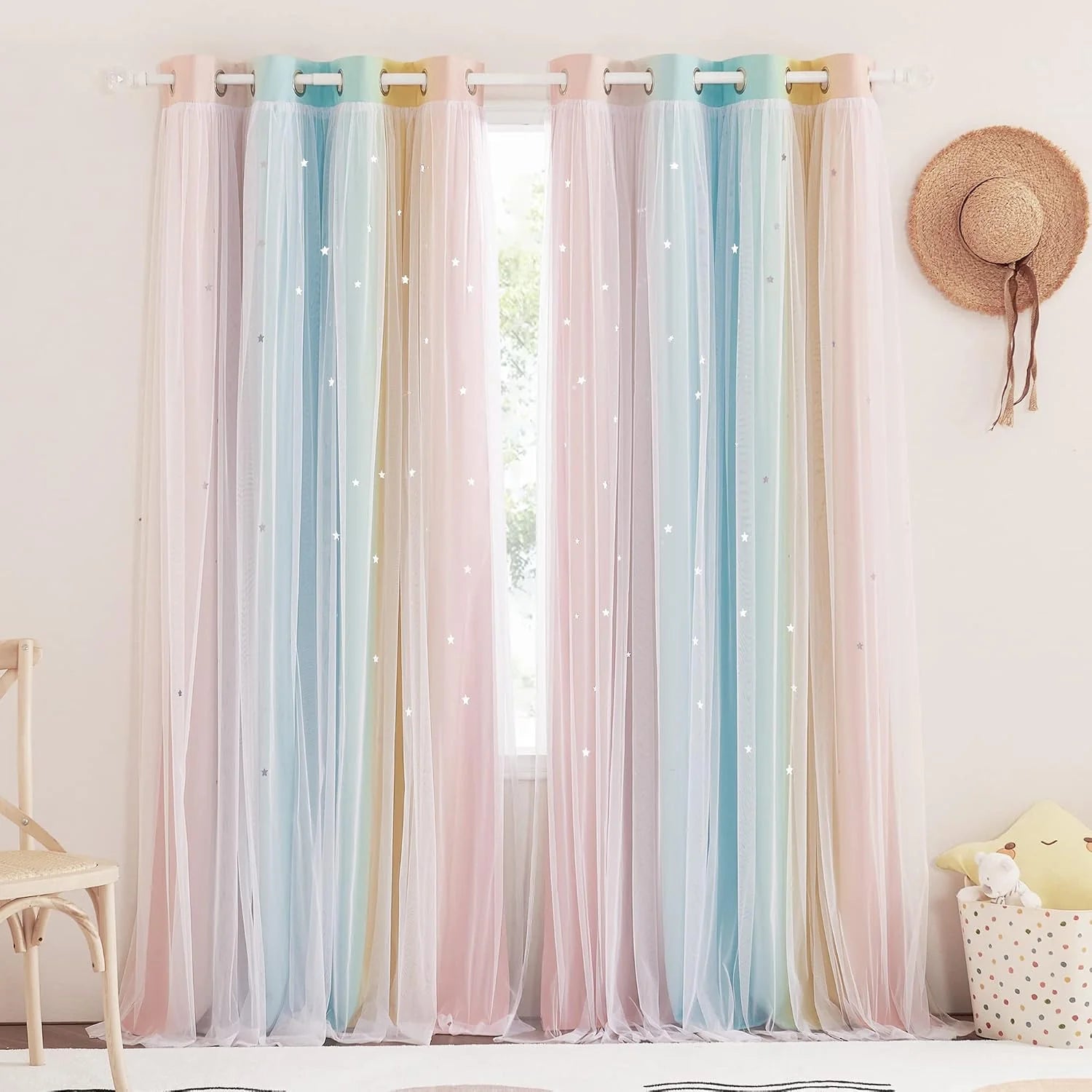 Pastel rainbow sheer curtains with star details hanging in a bright kids room