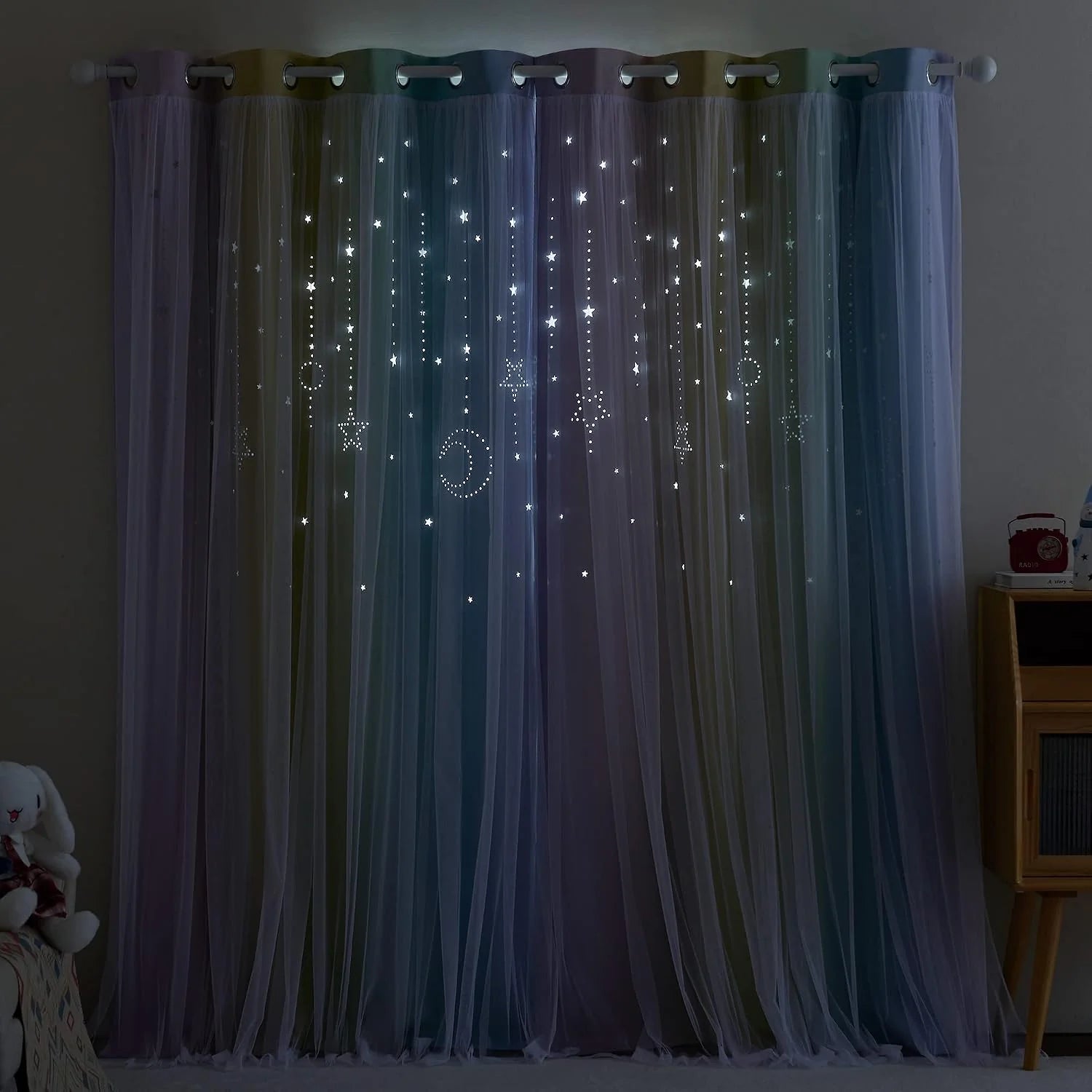 Pastel sheer grommet curtains with glowing star and moon cutouts in a kids room