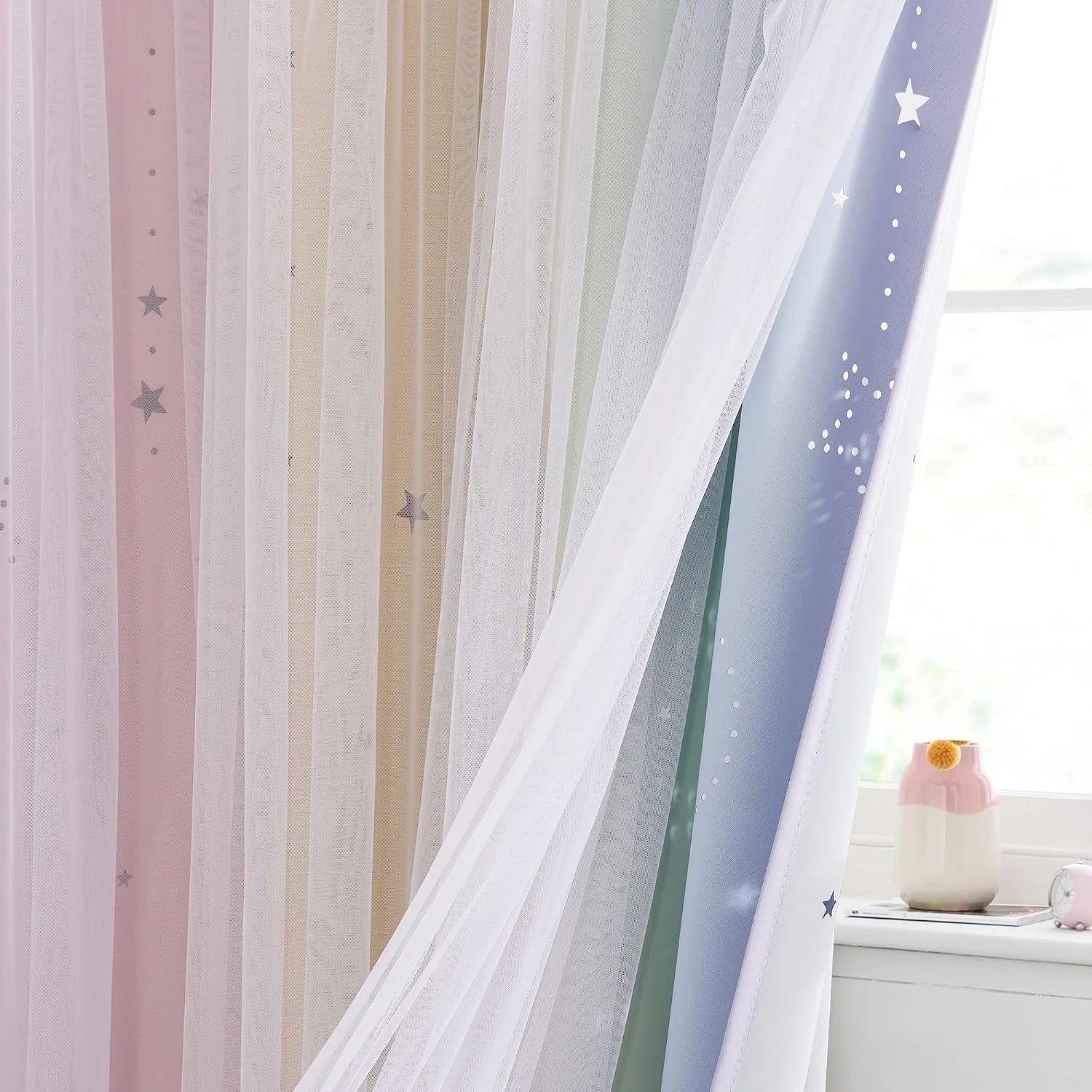 Pastel sheer curtains with star pattern layered over a bright kids room window