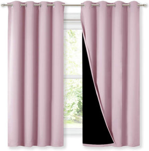 Pair of solid pink grommet top blackout curtains hanging on a silver rod, with one panel revealing its black lining against a window.