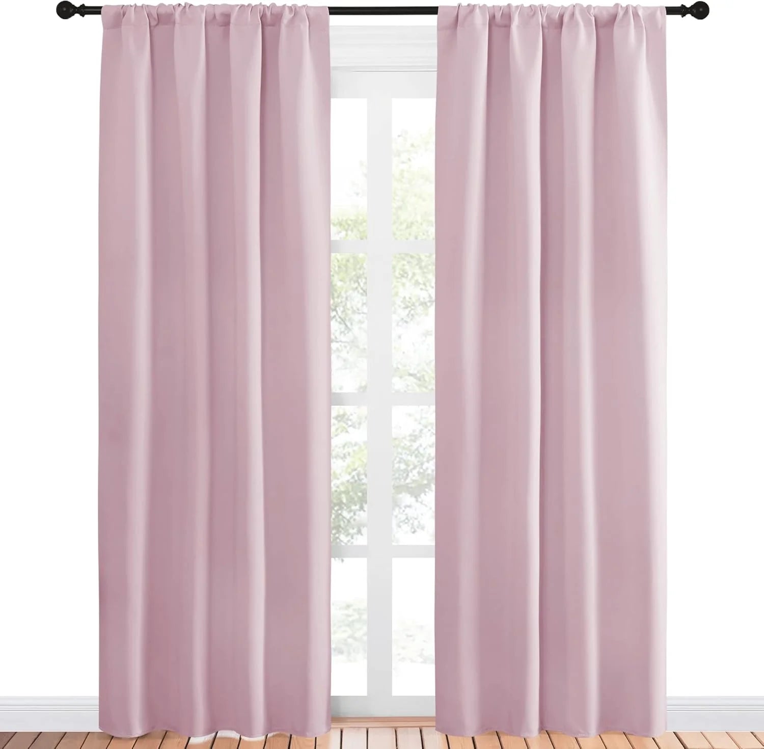 Two light pink rod pocket curtains hanging on a black rod over a window with a light wooden floor.