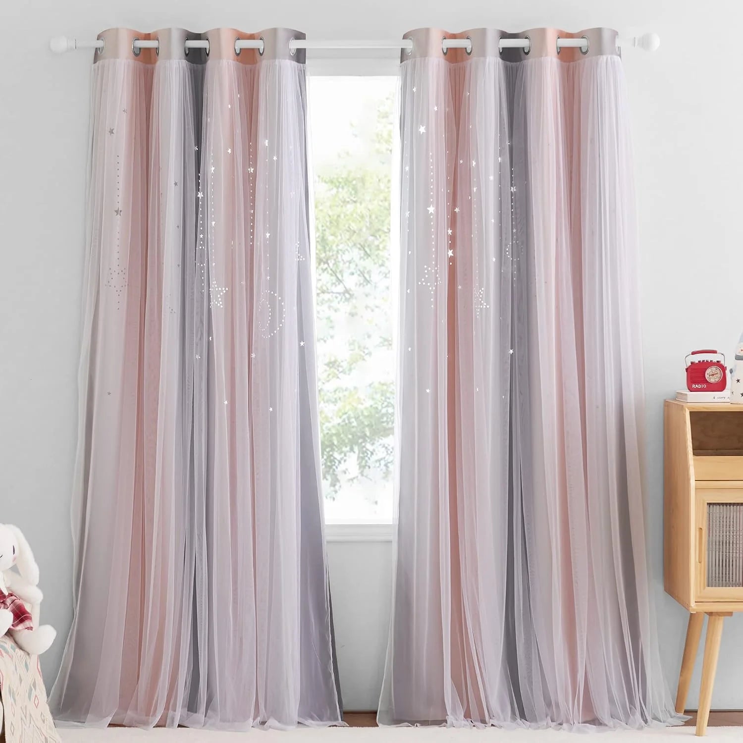 Pink and gray sheer star curtains with grommet top over a bright bedroom window