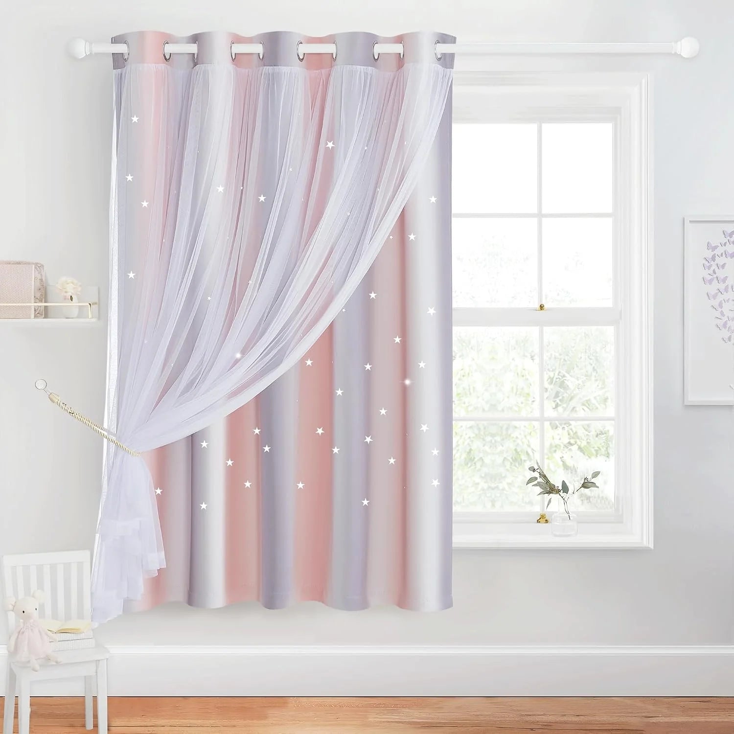 Pink and gray star curtains with white sheer overlay on a kids bedroom window