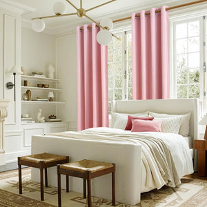 Solid pink grommet top blackout curtains hanging on large windows in a bright bedroom.
