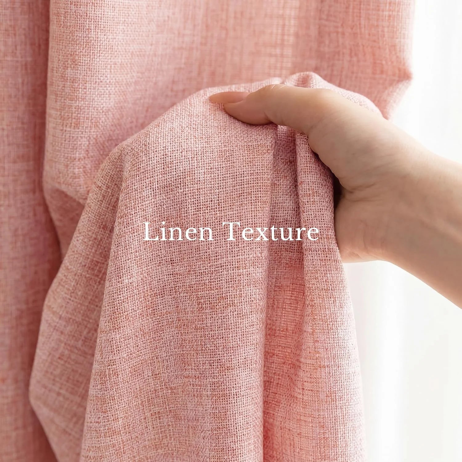 Close-up of a hand gently holding up a soft pink fabric, revealing its distinct linen texture and weave.