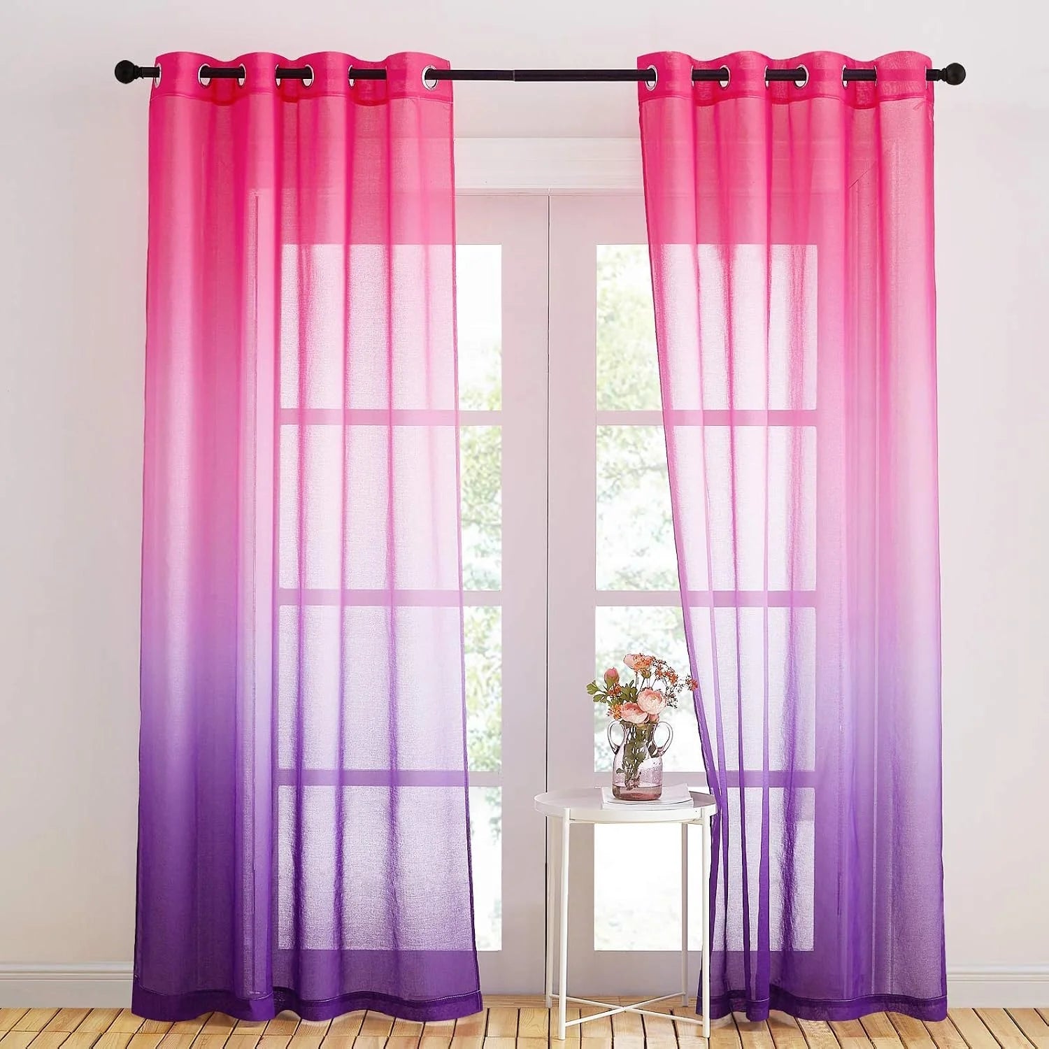 Pink to purple ombre sheer curtains with grommet top hanging over a bright window