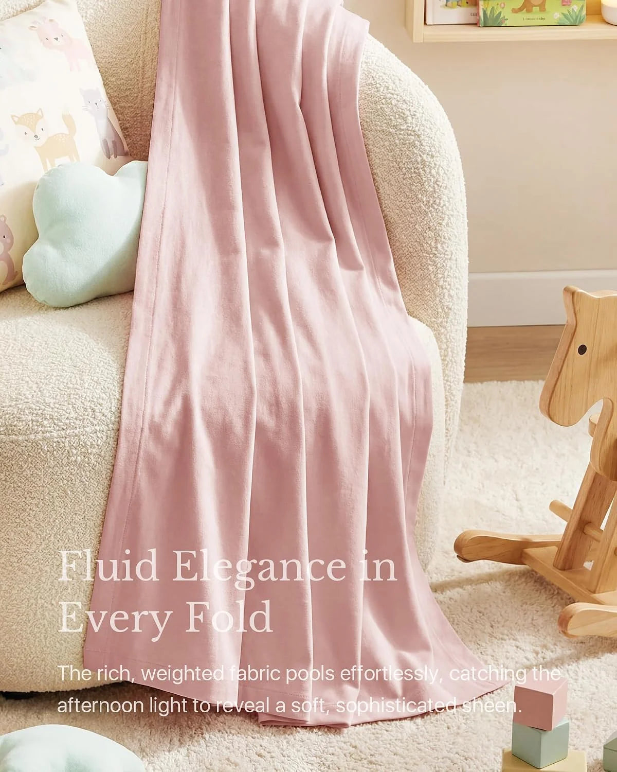 Soft pink satin throw blanket draped over a cream boucle chair in a nursery