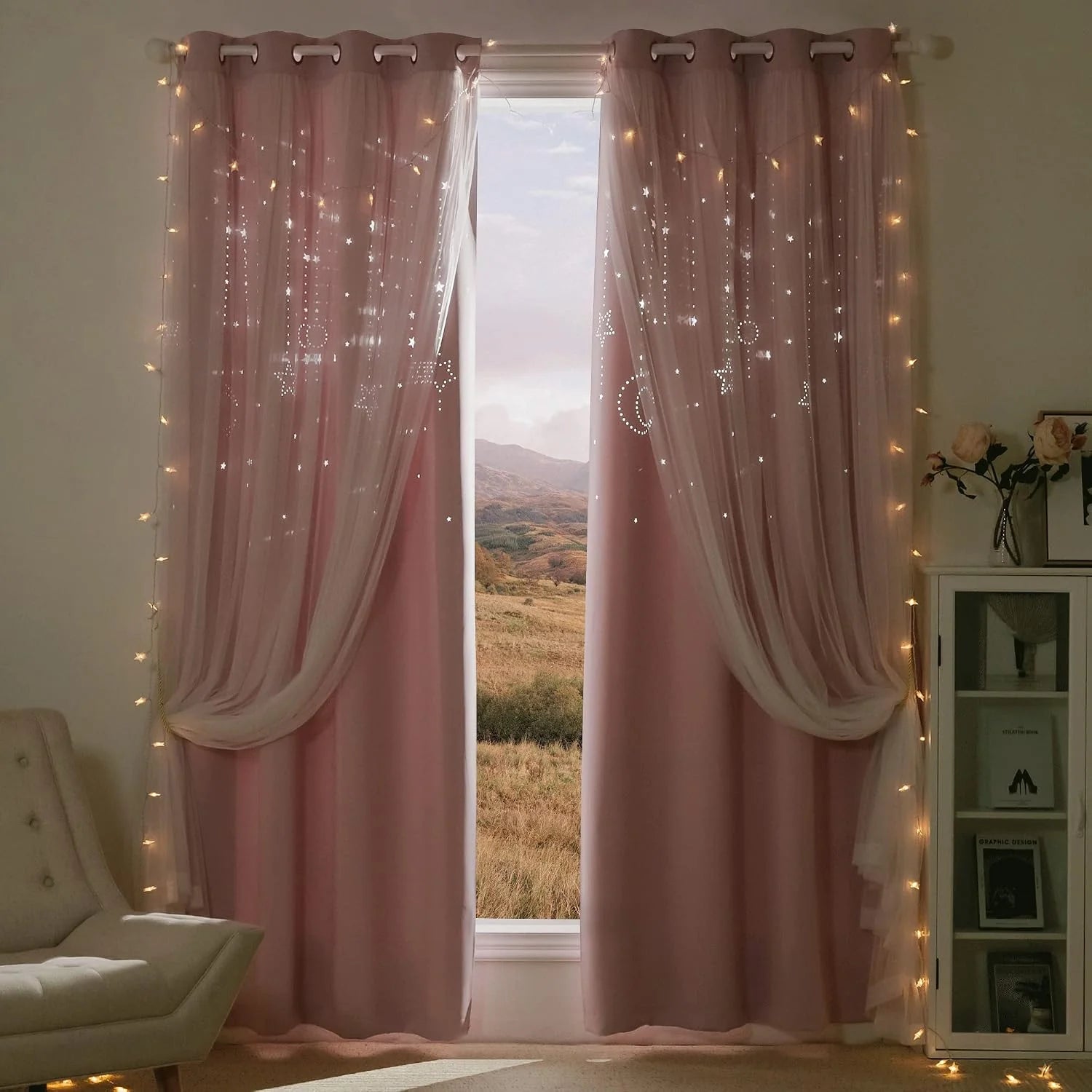 Pink layered curtains with sheer star and moon overlay and warm fairy lights