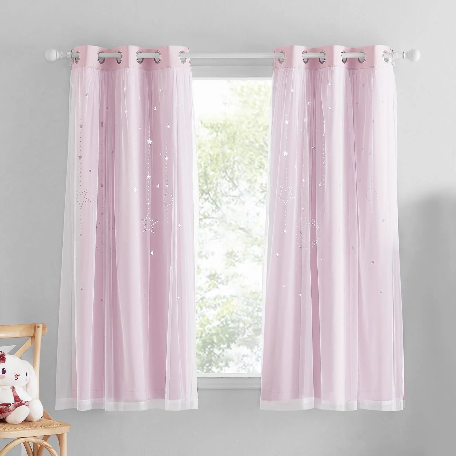Pink sheer kids curtains with white star print and silver grommets on a window