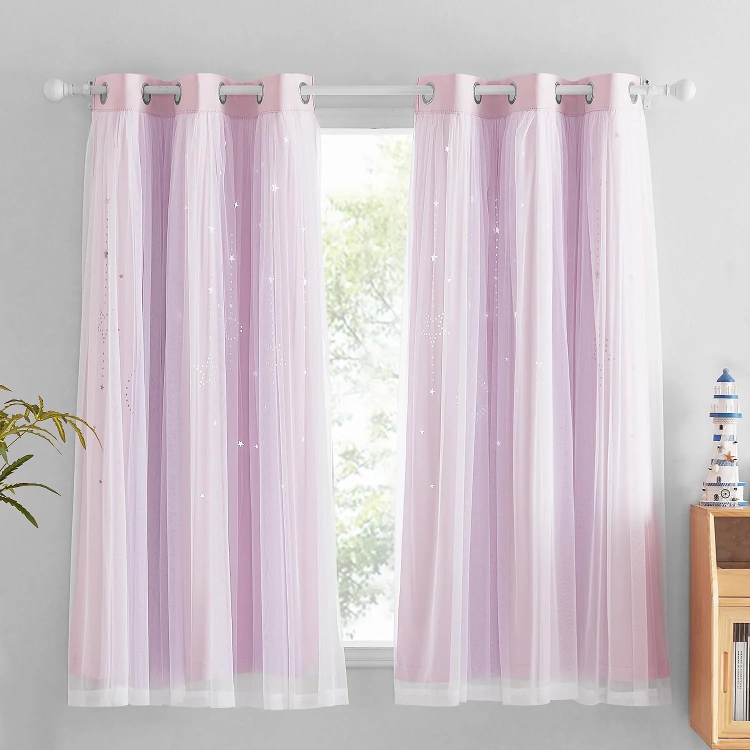 Soft pink sheer star curtains with silver grommets hanging on a white window rod