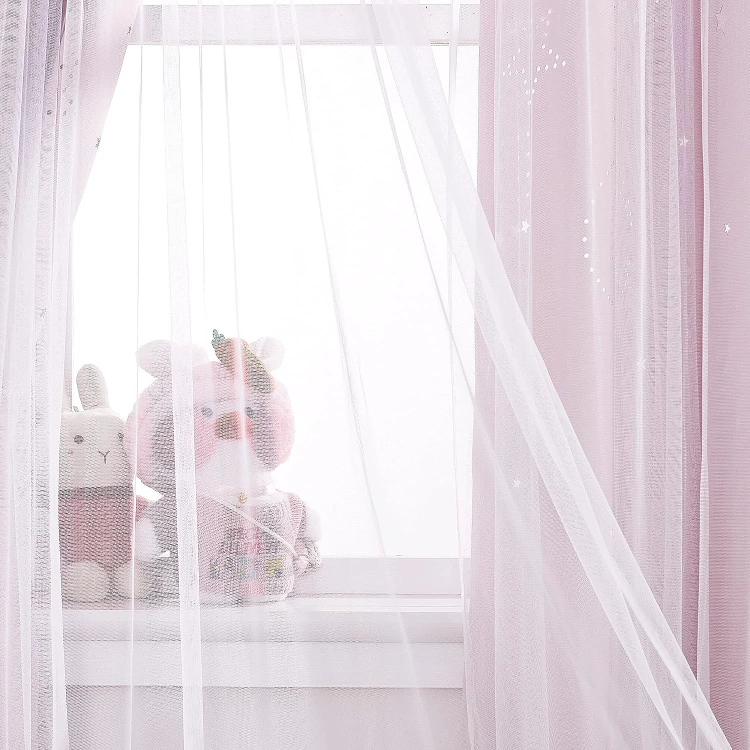 Soft pink sheer curtains with star details over a bright nursery window and plush toys