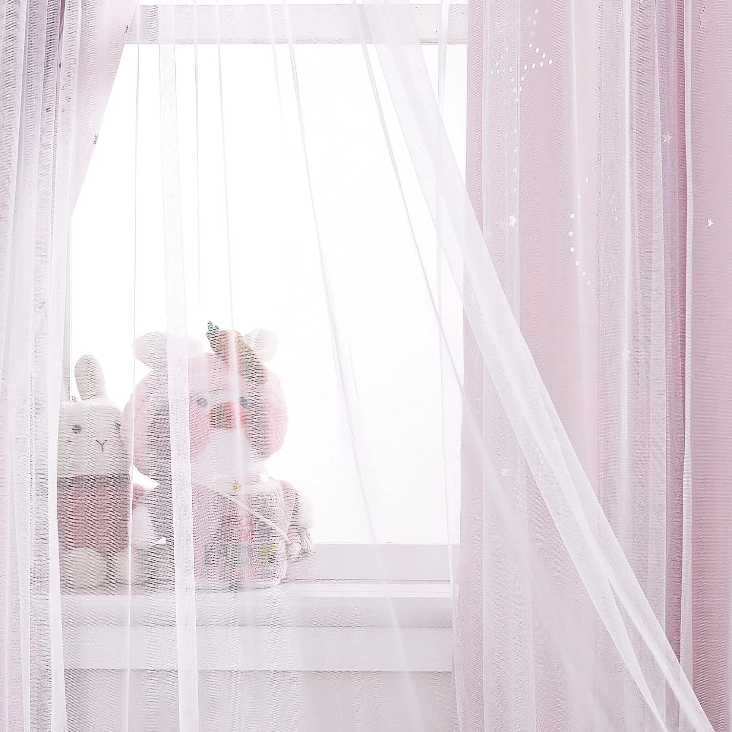 Pink sheer curtains with star details by a bright window in a soft kids room