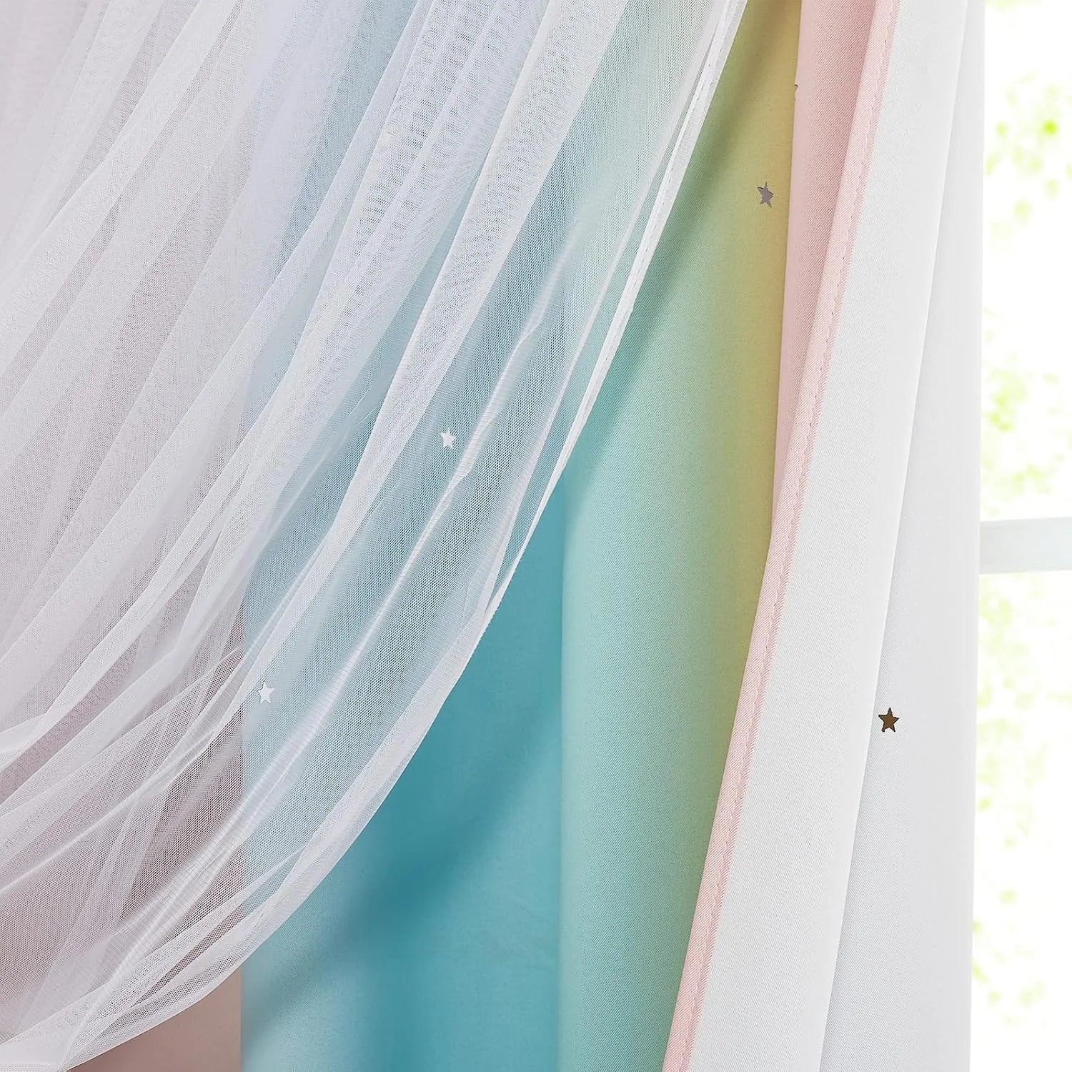 Soft pink sheer voile curtain with tiny star details hanging by a bright window