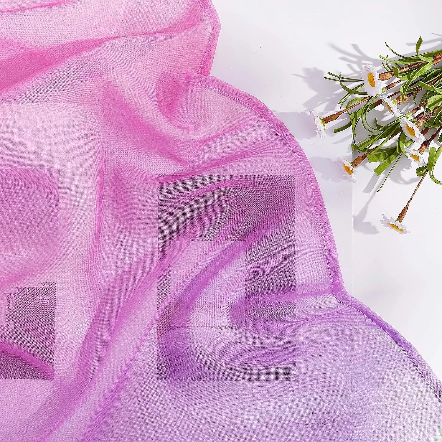 Soft pink sheer voile curtain fabric draped on white surface with small flowers