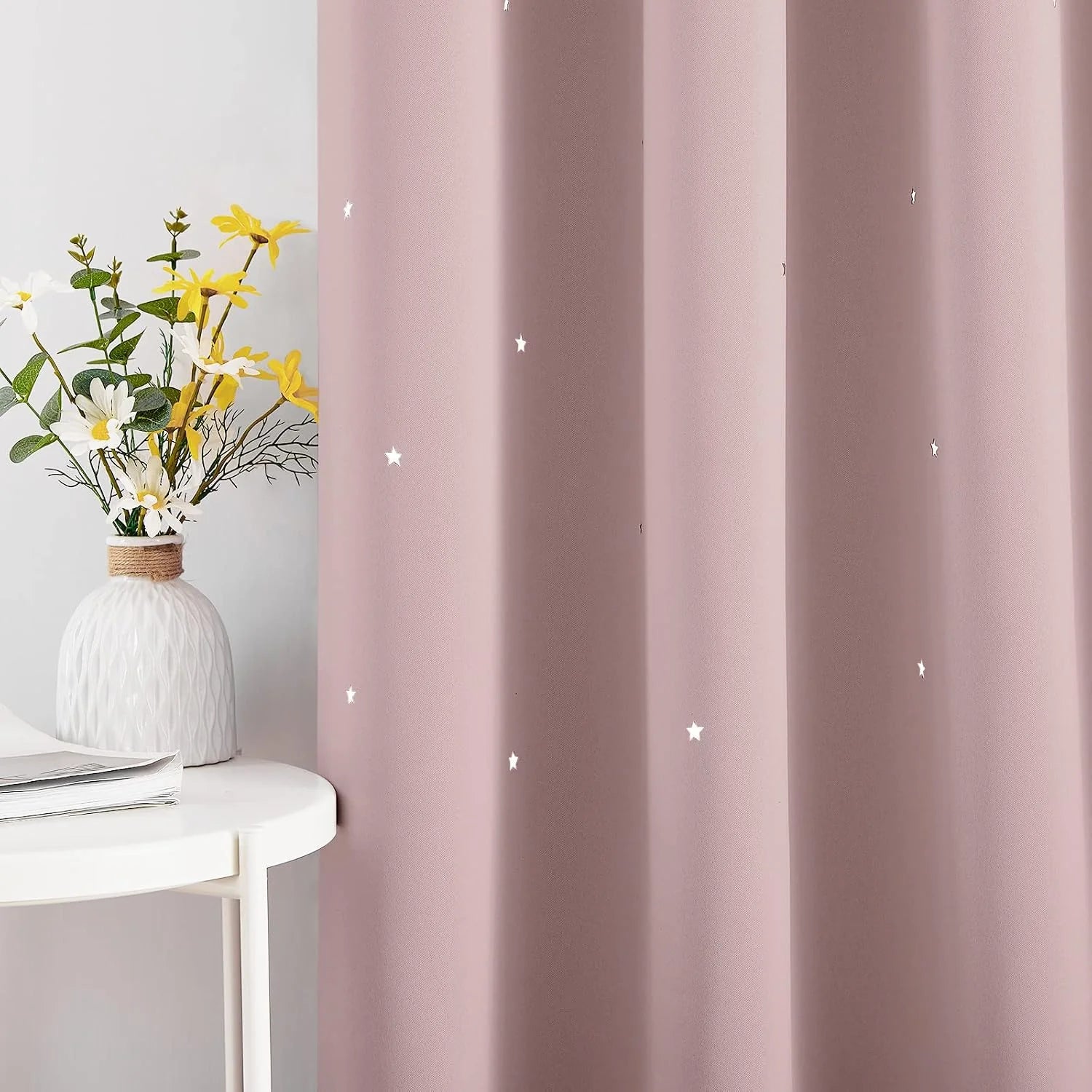Dusty pink curtain panel with small white star details beside a white side table