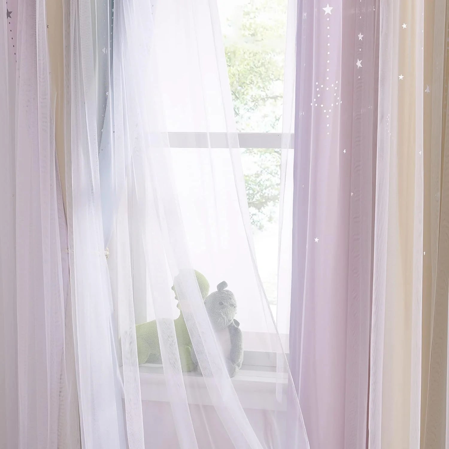 Soft pink sheer curtains with star cutout details hanging over a bright window