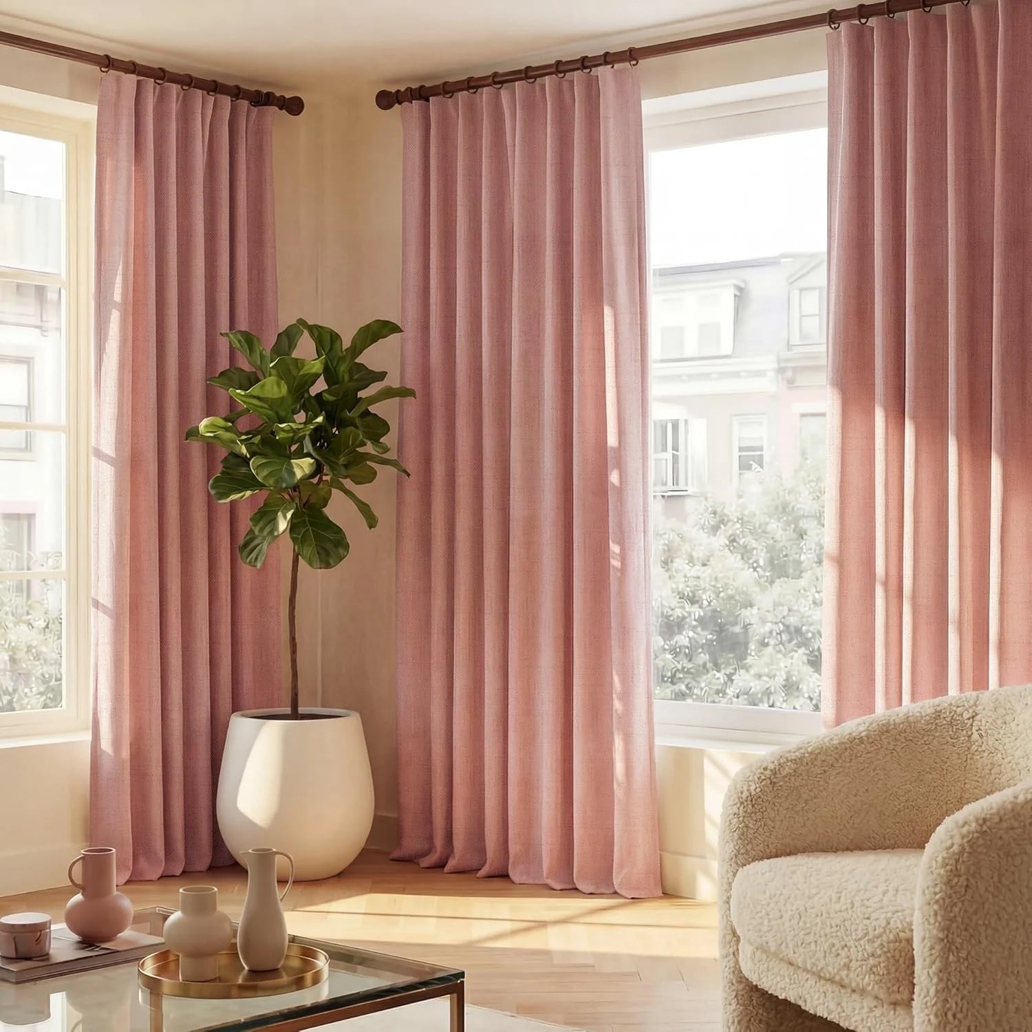 Full-length pink textured curtains on wooden rods in a bright, modern living room with a plant and armchair