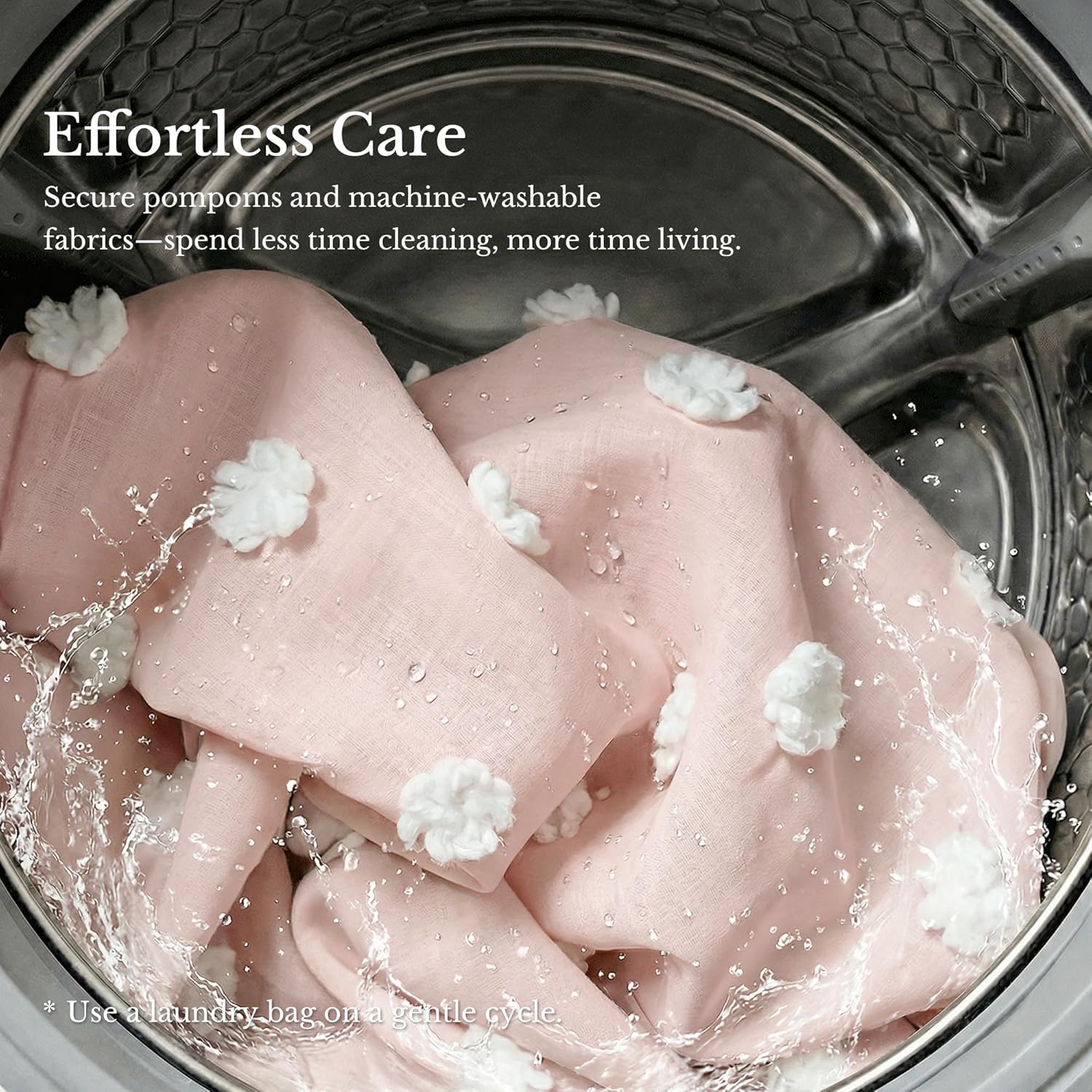 Pink fabric with secure white pom-poms washing in a machine, water splashing.