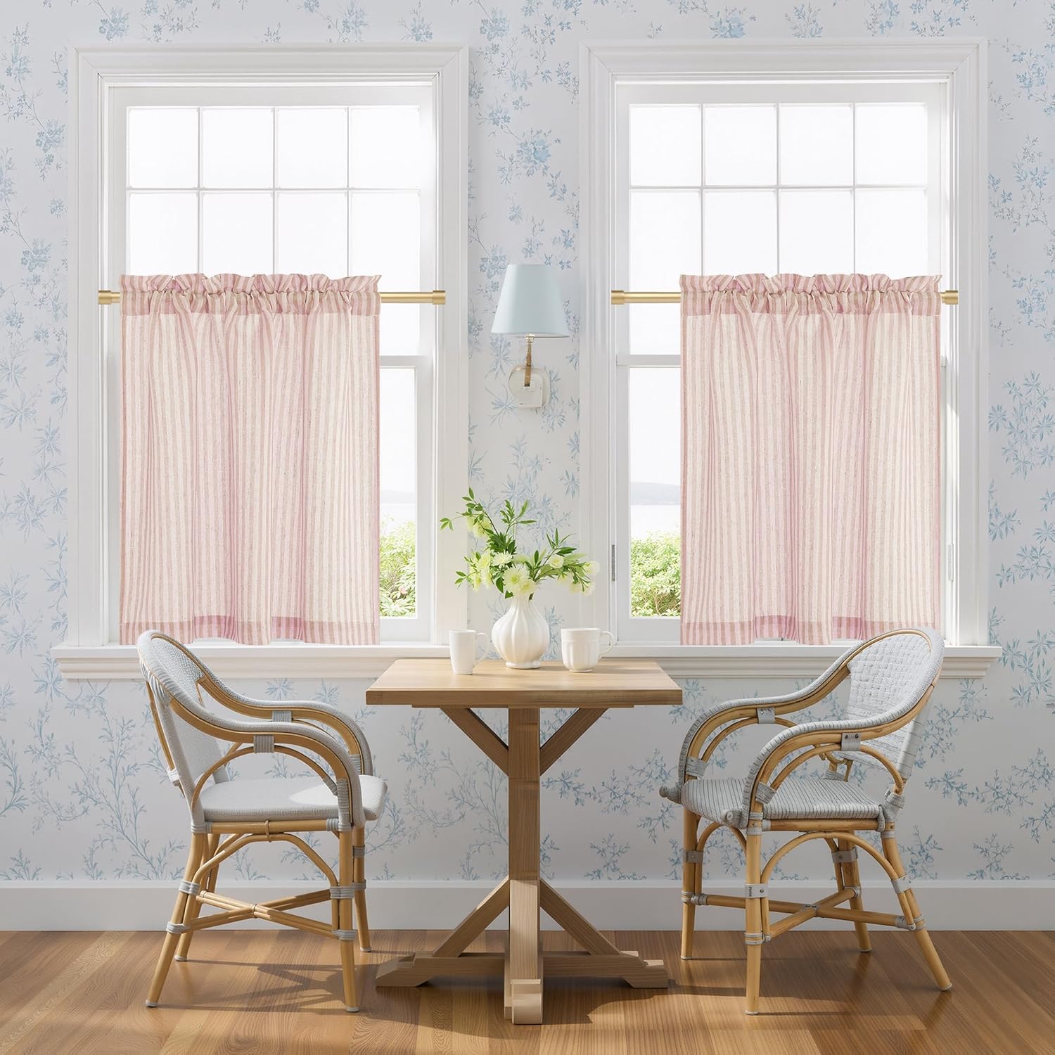 Two pink and white striped cafe curtains with a rod pocket design, softly filtering light in a bright kitchen window.
