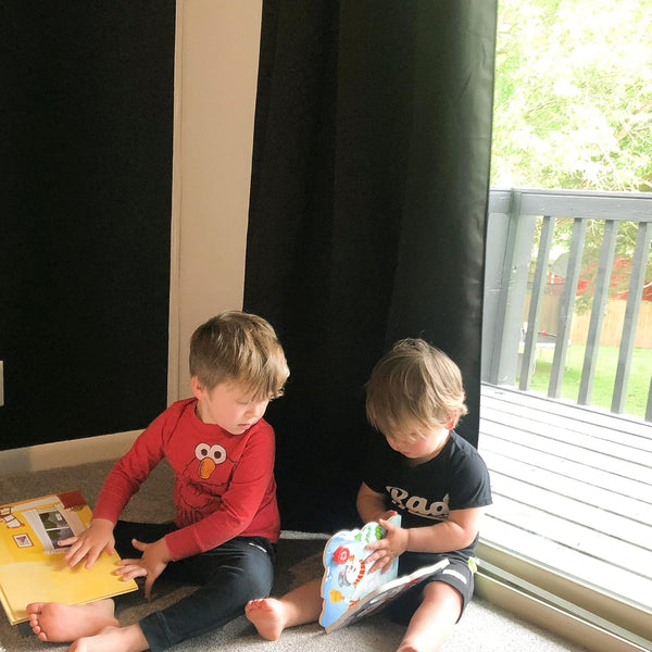 Plain black blackout curtain hanging over a glass door, providing privacy and room darkening.