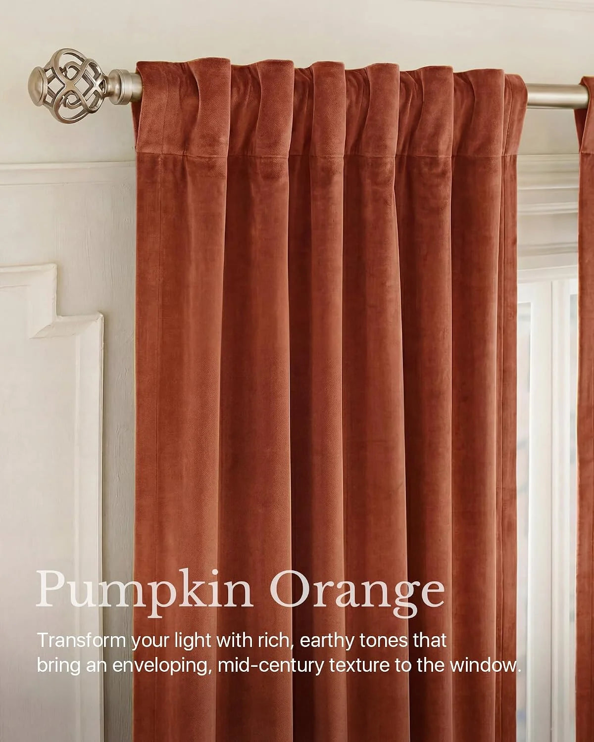 Pumpkin orange velvet curtain panels with pleated header on a brushed metal rod