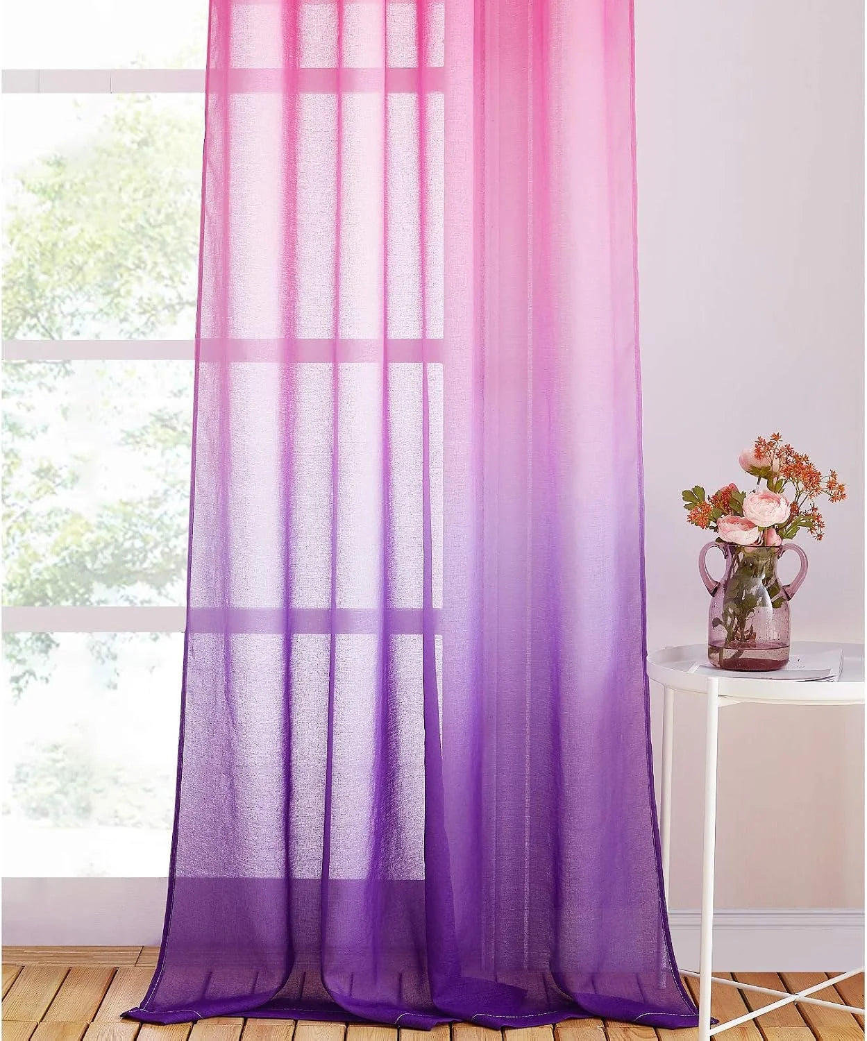 Purple ombre sheer curtain panel hanging by a bright window beside a white side table