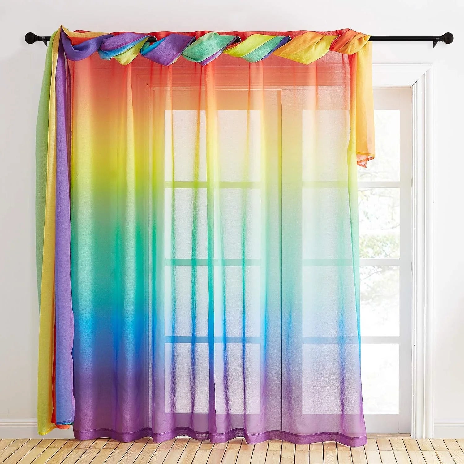 Rainbow ombre sheer curtain draped on a black rod over a bright white window