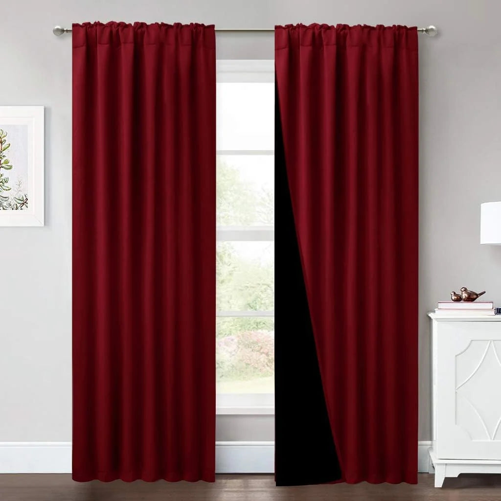 Deep red blackout curtains hanging on a silver rod in a bright modern room
