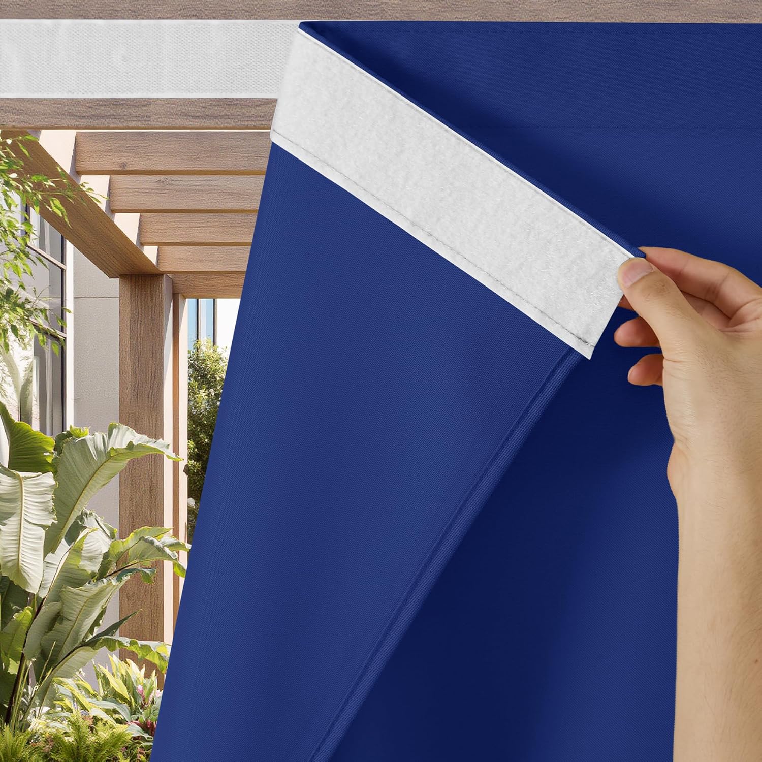 Hand attaching royal blue blackout window shade with white velcro strip. Outdoor patio background.