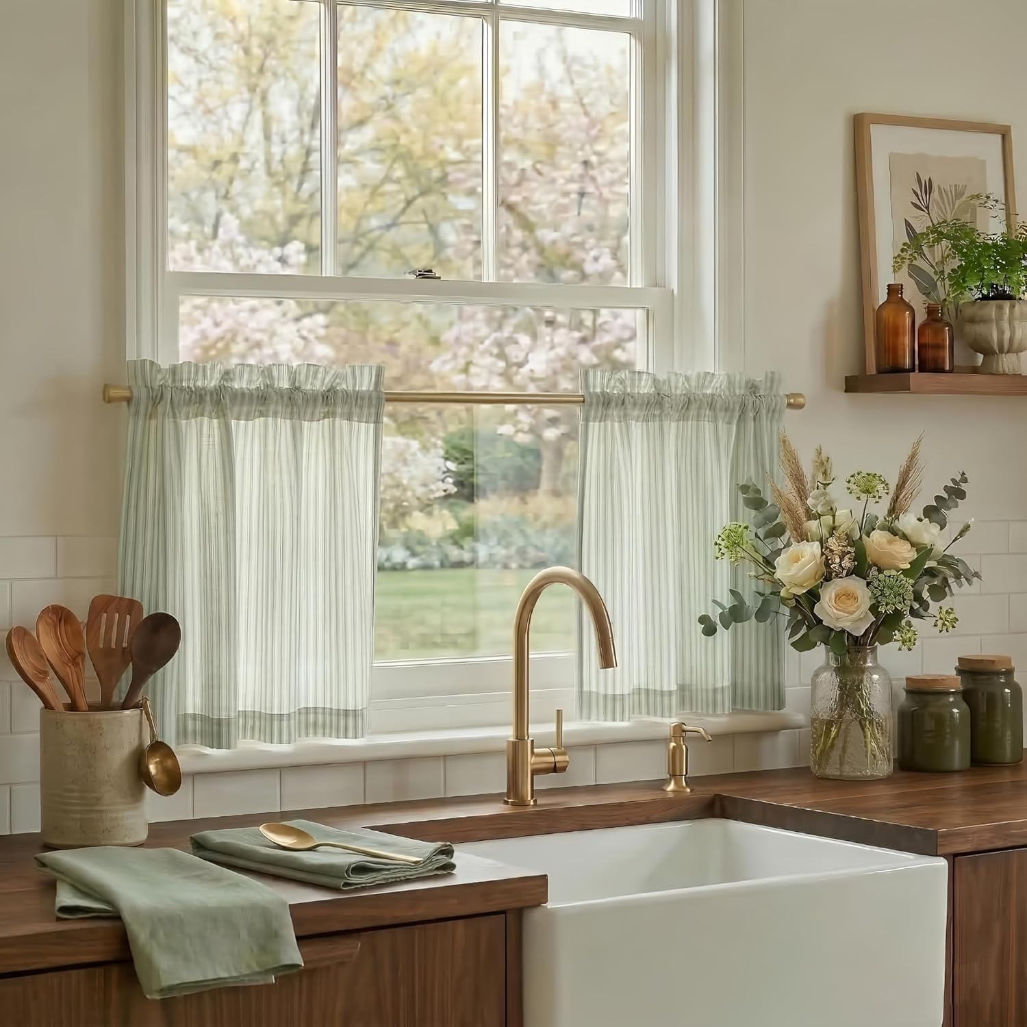 Ruffled sage green and white striped cafe curtains made of a light linen blend, hanging on a gold rod in a sunny kitchen window.