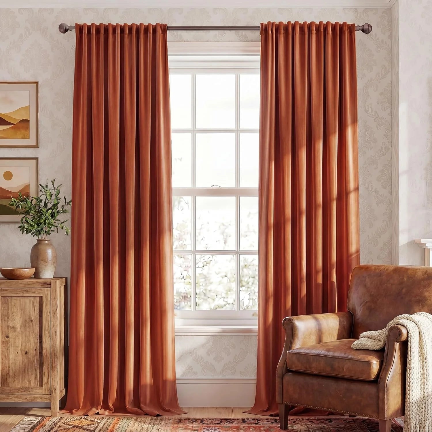 Rust velvet curtains on a window in a cozy living room with leather armchair