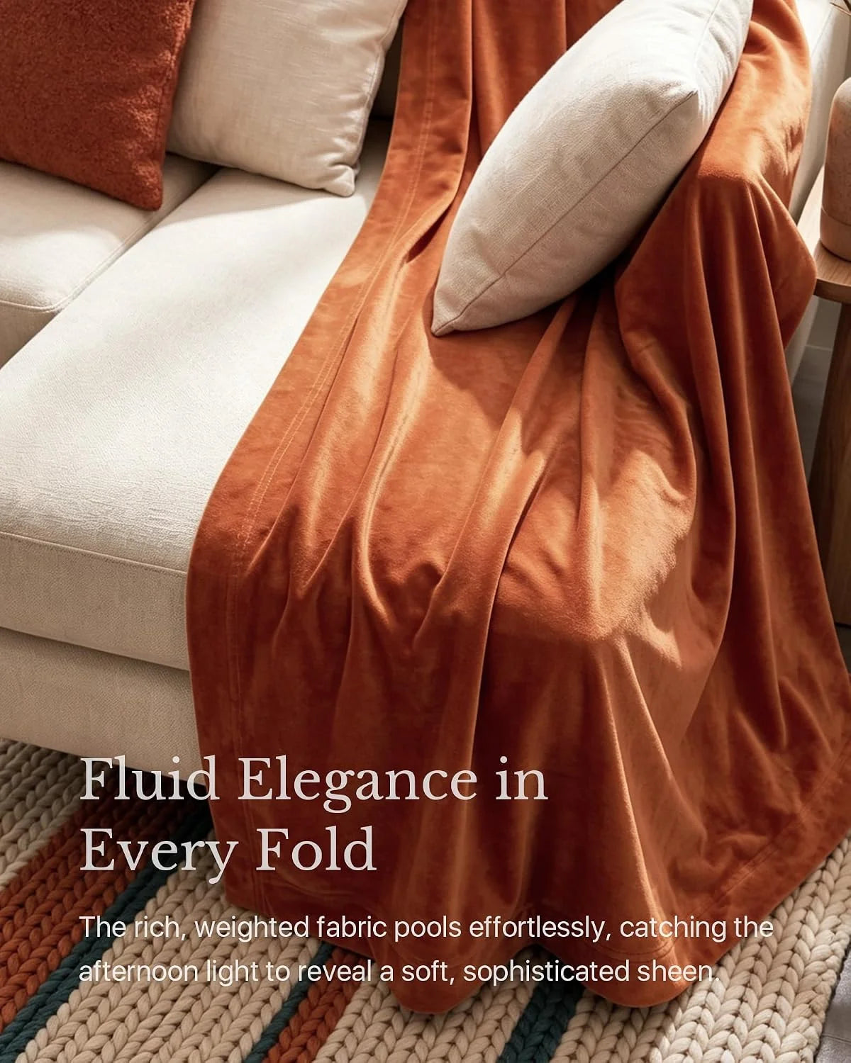 Rust velvet throw draped over a cream sofa with textured pillows in warm light