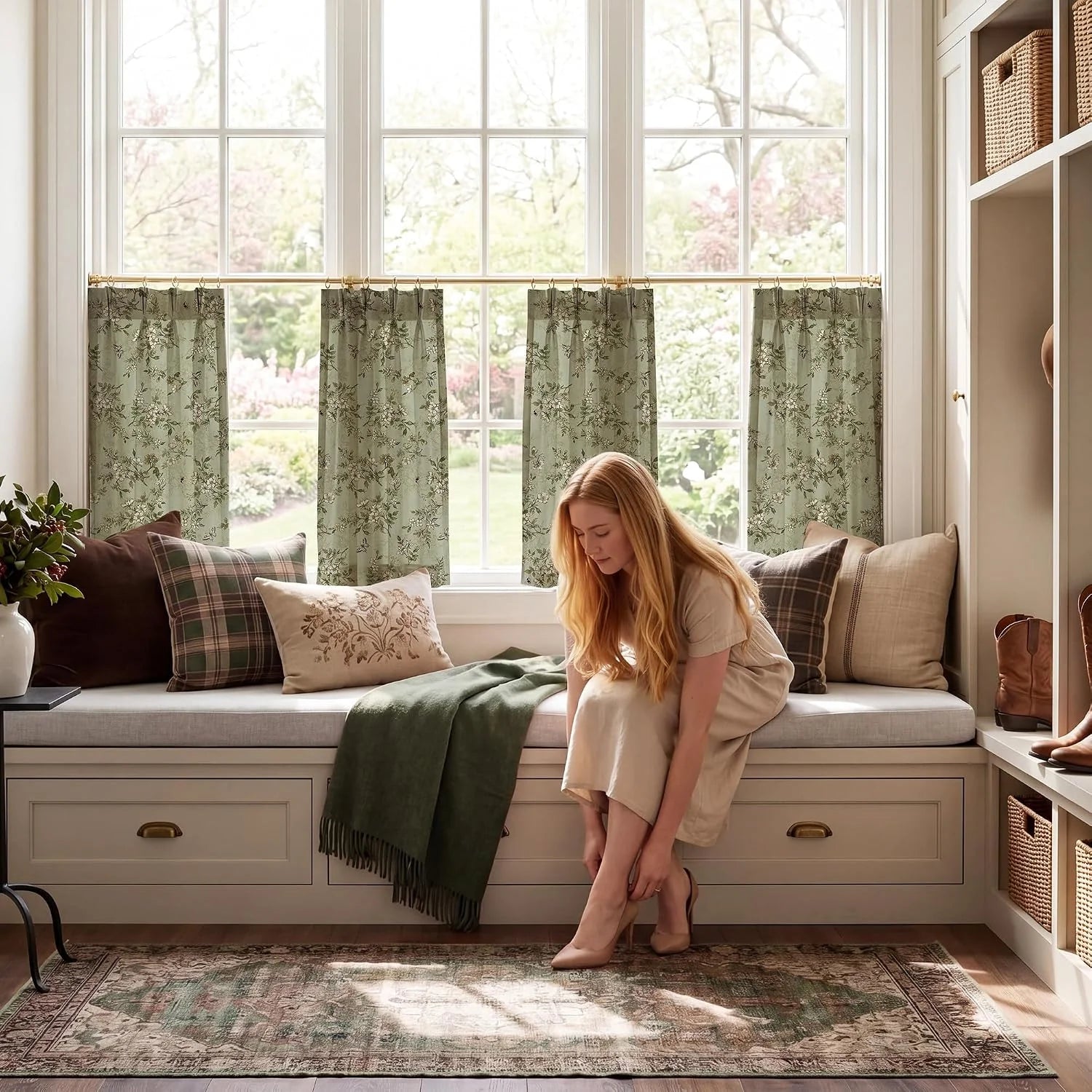 Sage floral cafe curtains on brass rods above a bright window seat with plaid pillows