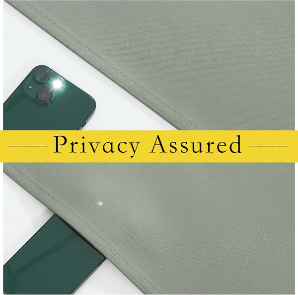 Close-up of sage green blackout fabric with visible weave, a smartphone flashlight on top demonstrates its light-blocking privacy.
