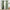 Pair of sage green grommet top blackout curtains, revealing the black lining, hanging on a window.