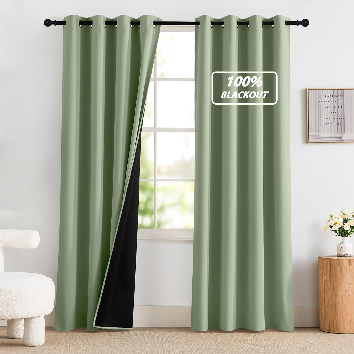 Pair of sage green grommet top blackout curtains, revealing the black lining, hanging on a window.