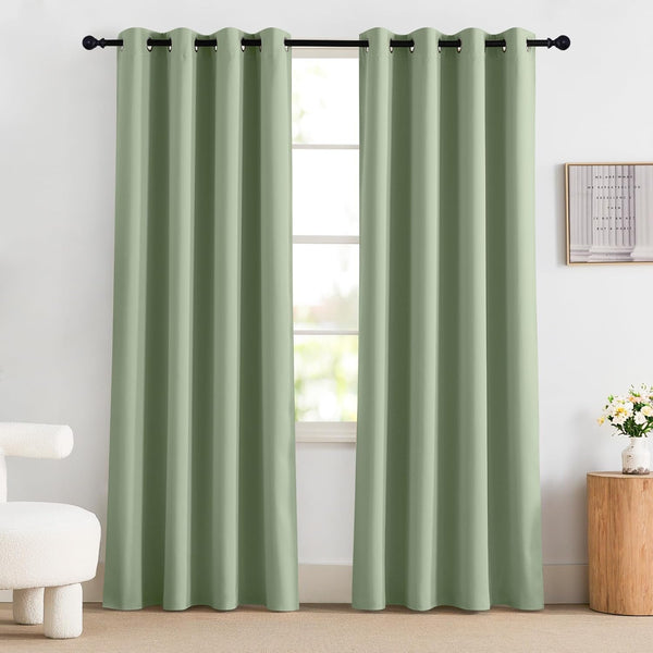 Pair of sage green blackout curtains with metal grommets on a black rod, covering a window in a modern room.