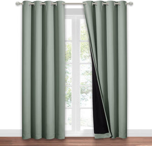Sage green blackout curtains with grommet top, one panel pulled back revealing black lining.