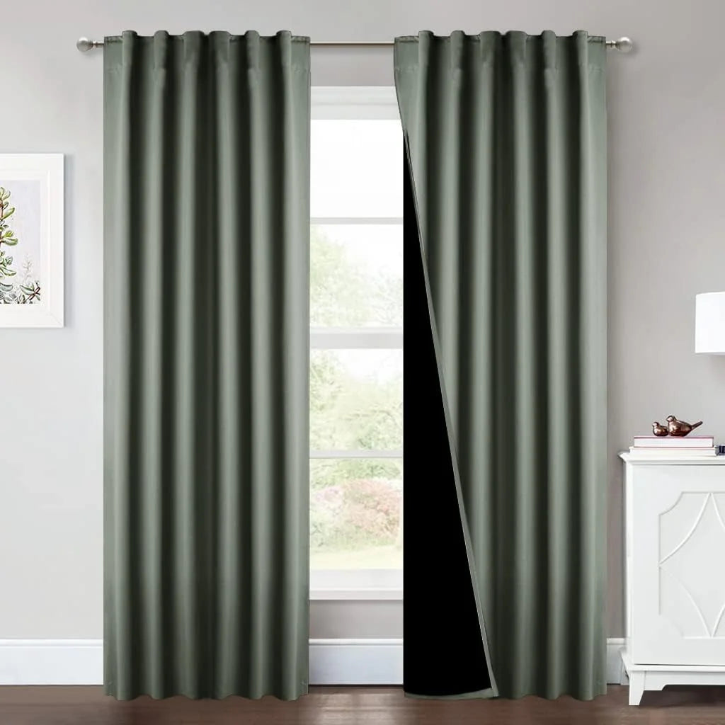 Sage green blackout curtains with soft pleats hanging on a silver rod in a bright room