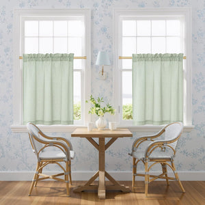 Pair of sage green gingham tier curtains with rod pocket top, hanging on brass rods.