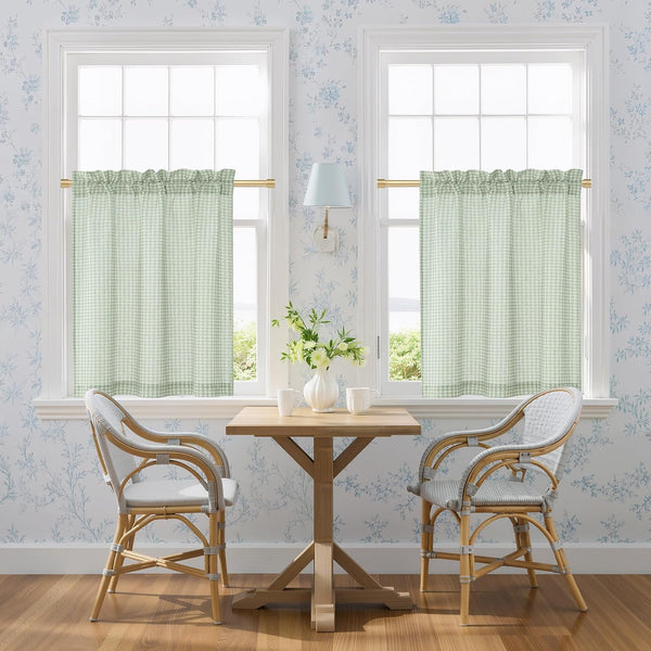 Pair of sage green gingham tier curtains with rod pocket top, hanging on brass rods.