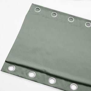 Folded sage green blackout curtain panel with visible silver grommet rings along the top.