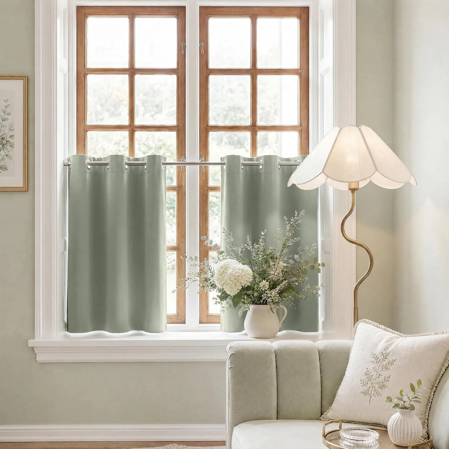 Sage green grommet cafe curtains on a wooden window with a vase of white flowers and a floor lamp.
