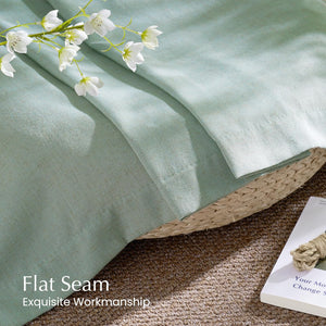 Close-up of natural sage green linen-blend fabric, highlighting a neat flat seam and fine texture.